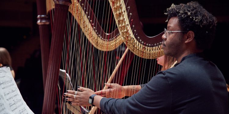 Harpist with hands on the strings in a rehearsal