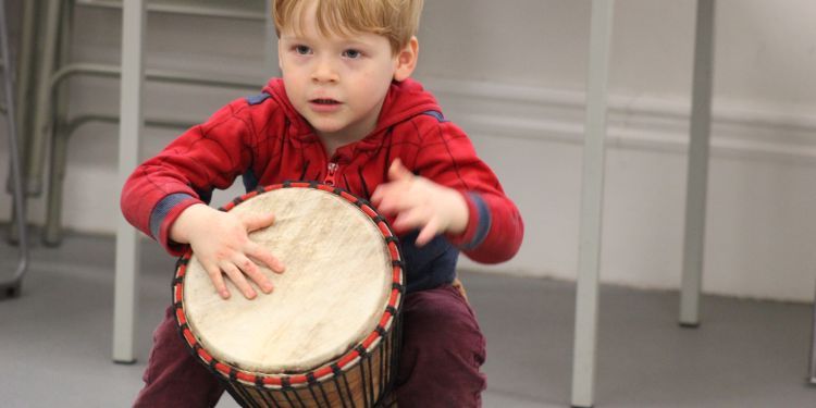 a young child drumming on a djembe