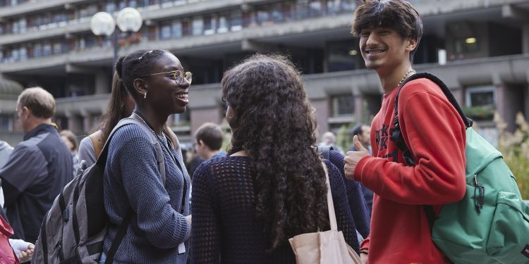 Group of three smiling students outside