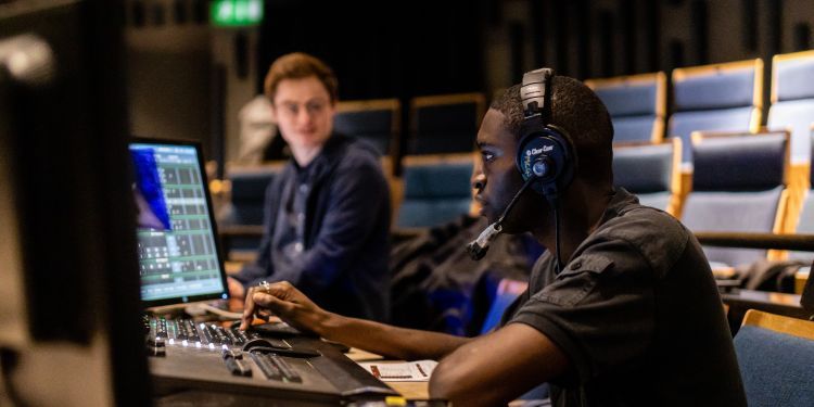 Guildhall students working at lighting desks during a technical rehearsal