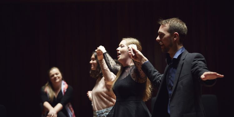 singers holding hands doing dance sequence