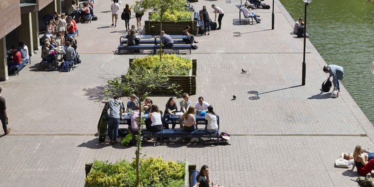 Lakeside terrace shot from above on a sunny day with students eating lunch and socialising outside