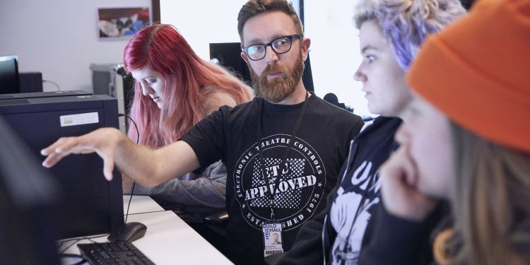 Lecturer teaching students at a computer