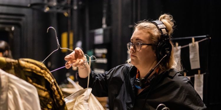 Costume student adding costumes to a rail