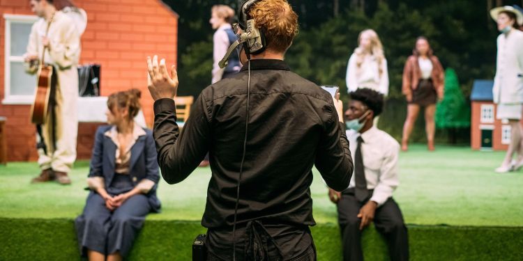 Stage Manager wearing headset and gesturing while actors are on stage