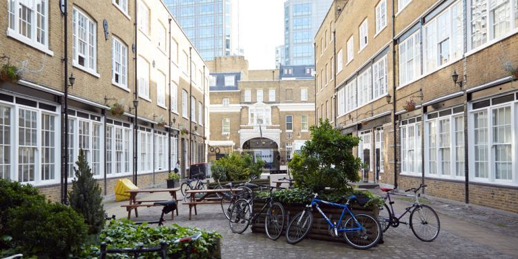 paved courtyard with bikes, benches and trees, surrounded by yellow brick buildings