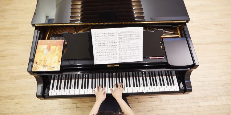 Pianist shot from above with hands on piano in a practice room