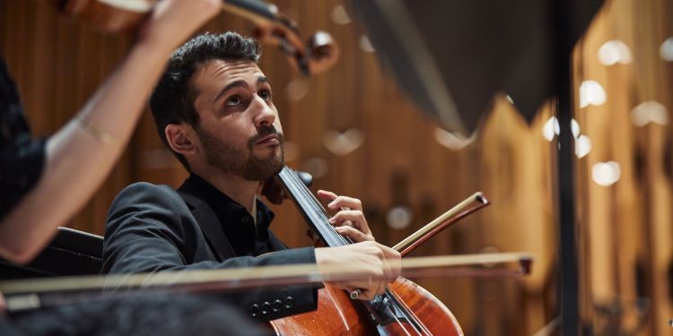 Cellist looks up off camera at the conductor