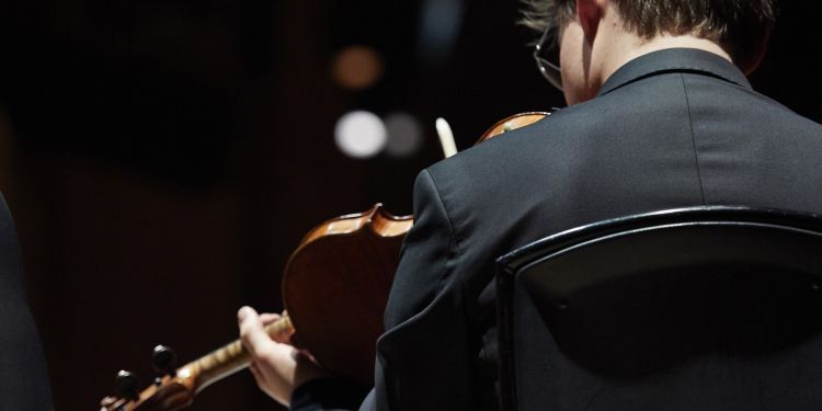 Violinist in a chair reading music while performing