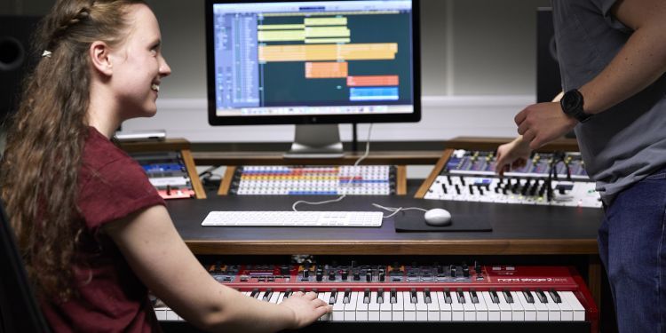 Two students at an electronic music workstation in a studio