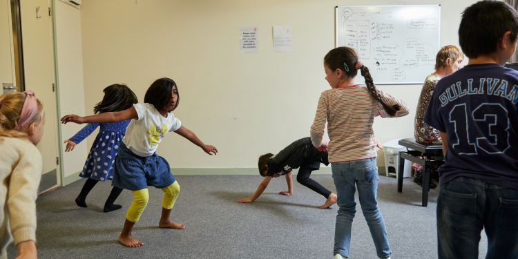 Six young children are making shapes with their arms and legs. One of them is crawling on the ground.