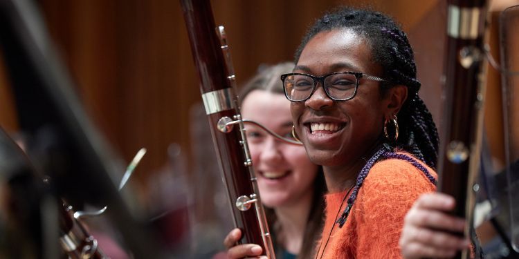 Wind players smile at the camera while holding instruments