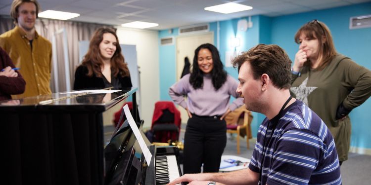 Music Therapy students in class around a piano