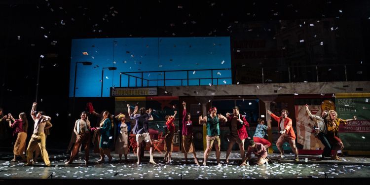 Banknote props raining down on stage as chorus and singers grab them from the air