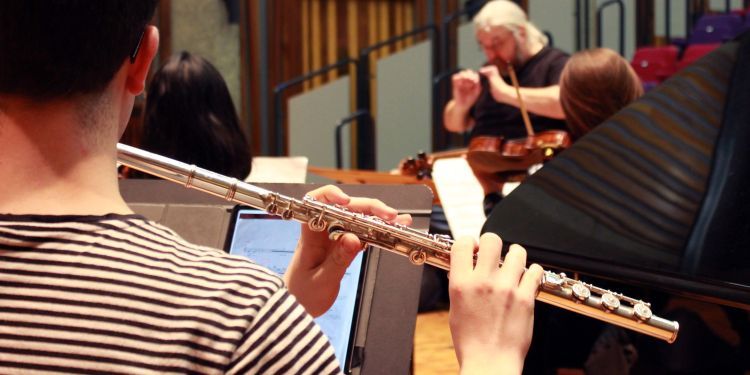 Flute player during an Ubu Ensemble rehearsal, with Conductor out of focus in the background