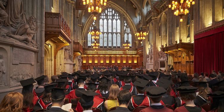 Students in graduation gowns wait in the Great Hall