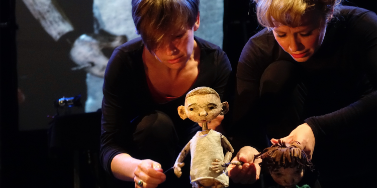 Two white female puppeteers performing in Hansel and Gretel