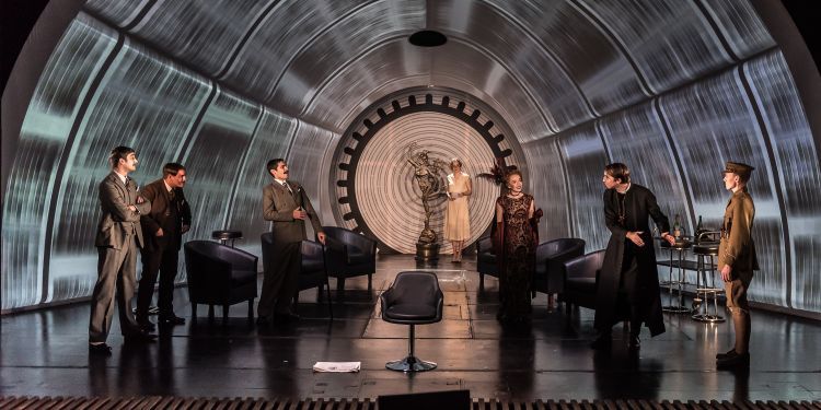 Actors on a stage in front of a large dome with video projections on