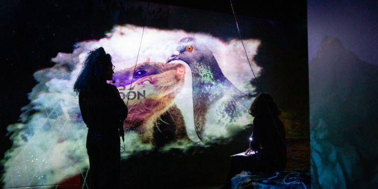 Staff member wearing headset silhouetted against a video projection