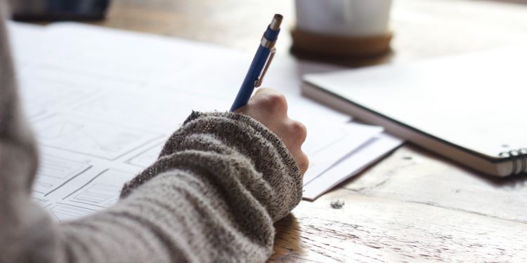 A person using a pen to write on paper