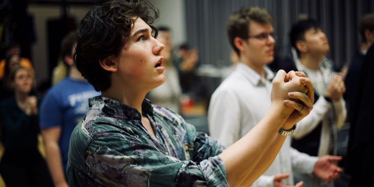 Opera singer holds his arms out in front of him, cupping his hands