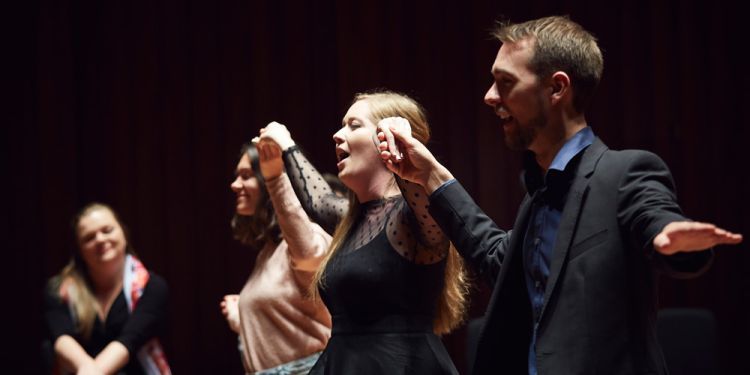 performers holding hands mid-performance on stage