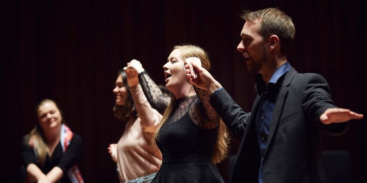 performers holding hands mid-performance on stage 