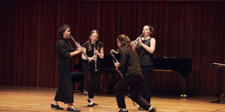 Four female clarinettists playing in a circle