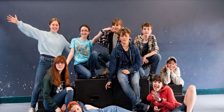 Nine students pose on a black platform 