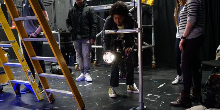 Project participant rigging a light in a theatre.
