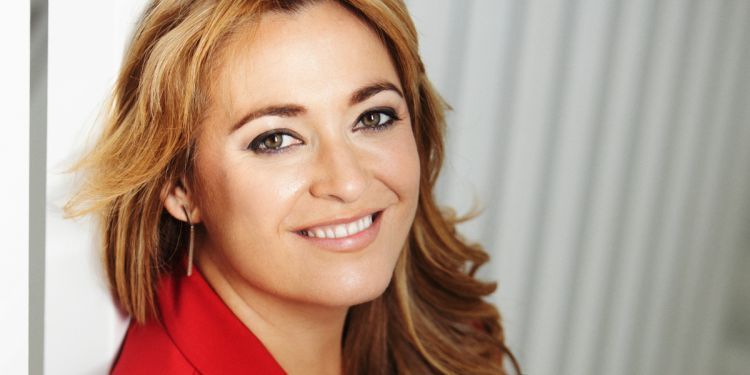 Laura Ruiz Ferreres, smiling, holding clarinet and wearing red jacket