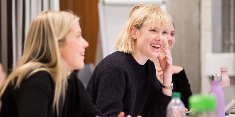 Women writing in a classroom and smiling