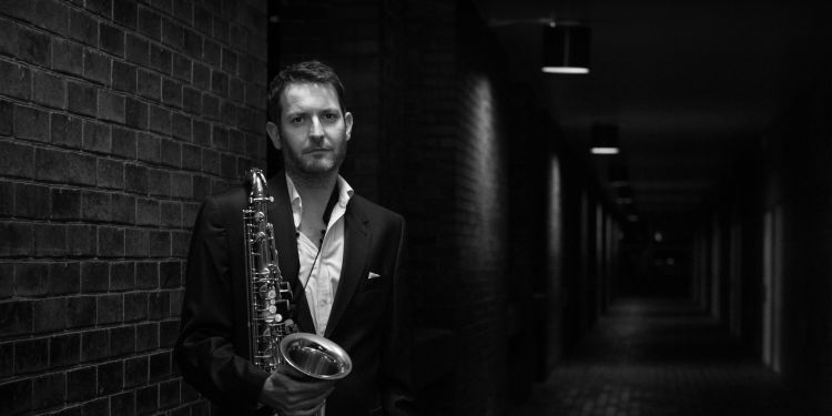 Black and white image of Ollie Weston holding a saxophone 