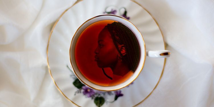 Image of a woman in the reflection of a cup of tea