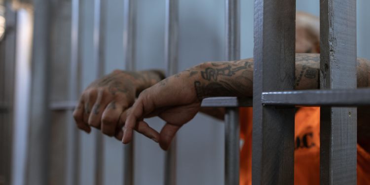 Hands hanging out of a prison cell