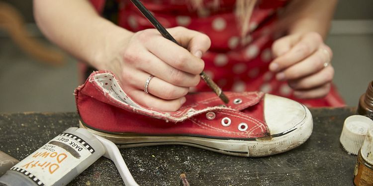 close up on participant hand holding a brush while using ageing technique on shoe