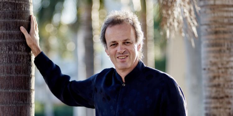 David Selig standing outside leaning on tree trunk