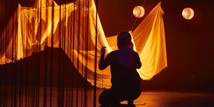 MACPT students on stage with orange cloth set design