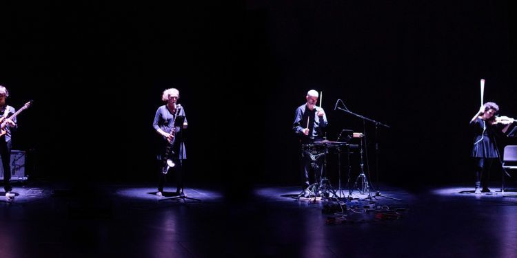 The four members of the Plus Minus Ensemble performing against black background