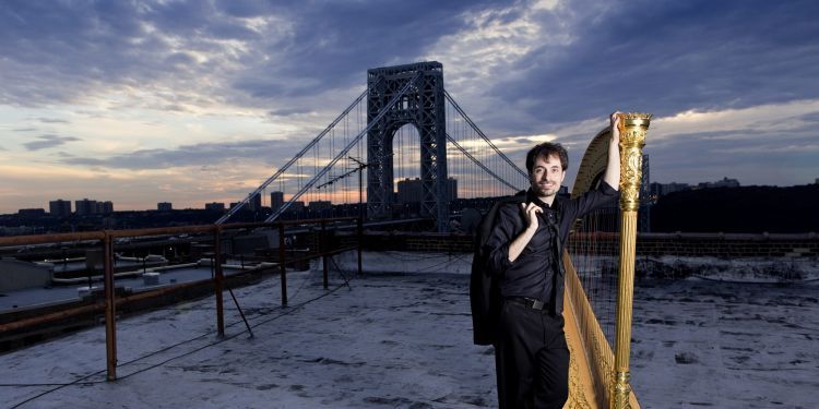 Sivan Magen standing next to golden harp in snow next to bridge