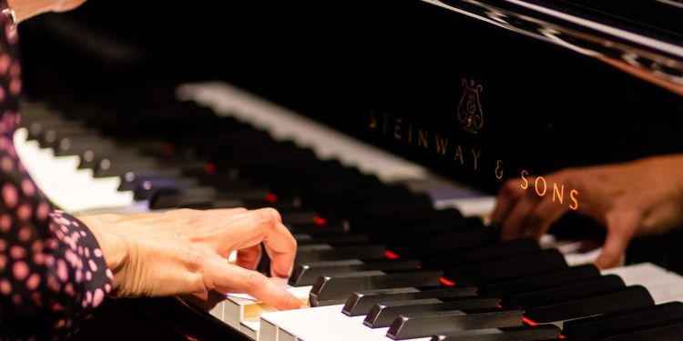 Zoomed in photo of a students hands playing a piano