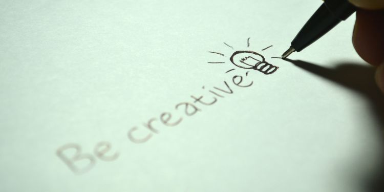 Be Creative is written on a piece of paper with a drawn lightbulb