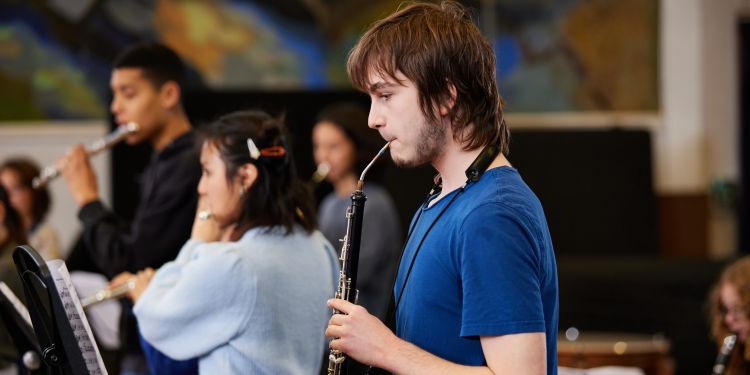 A boy in a blue t-shirt plays the oboe