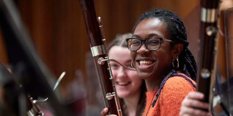 Students smiling in an orchestral rehearsal