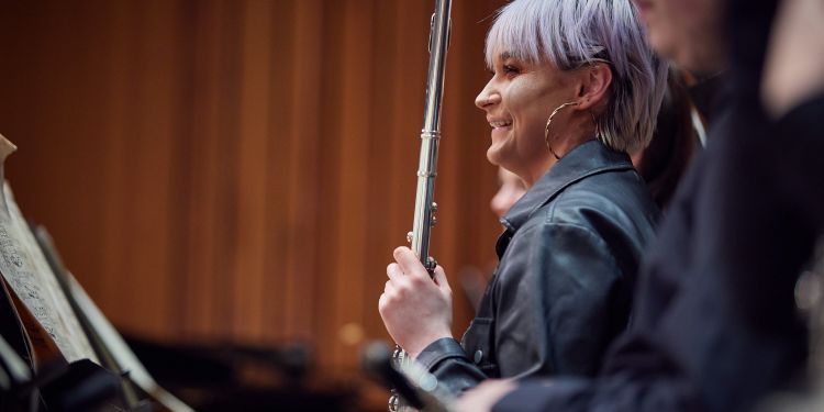 Female student smiling and holding a wind instrument