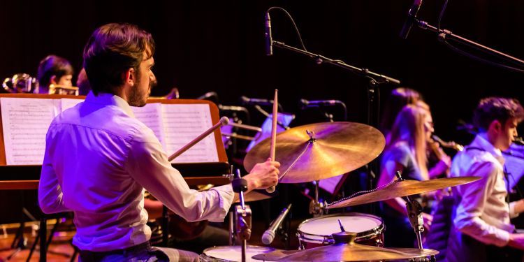 Photo from the back of a male student playing the drums as part of the Big Band