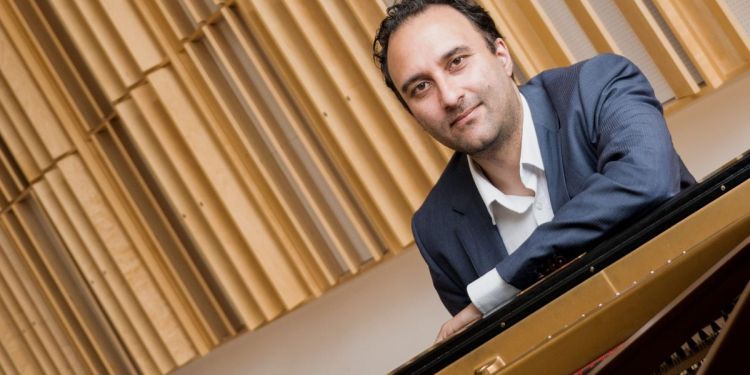 Photo of Søren Rastogi sat at a piano smiling