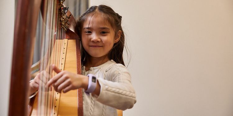 Young musician smiling and playing the harp