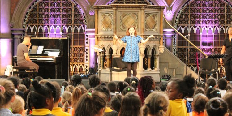A woman singing on the stage with the audience made up of young people