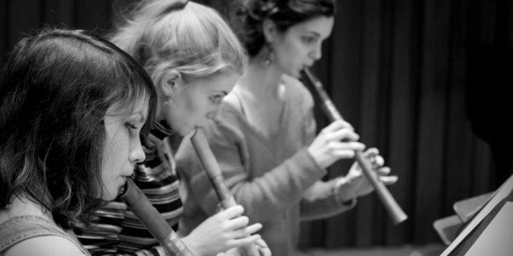 Three students playing the recorder in black and white